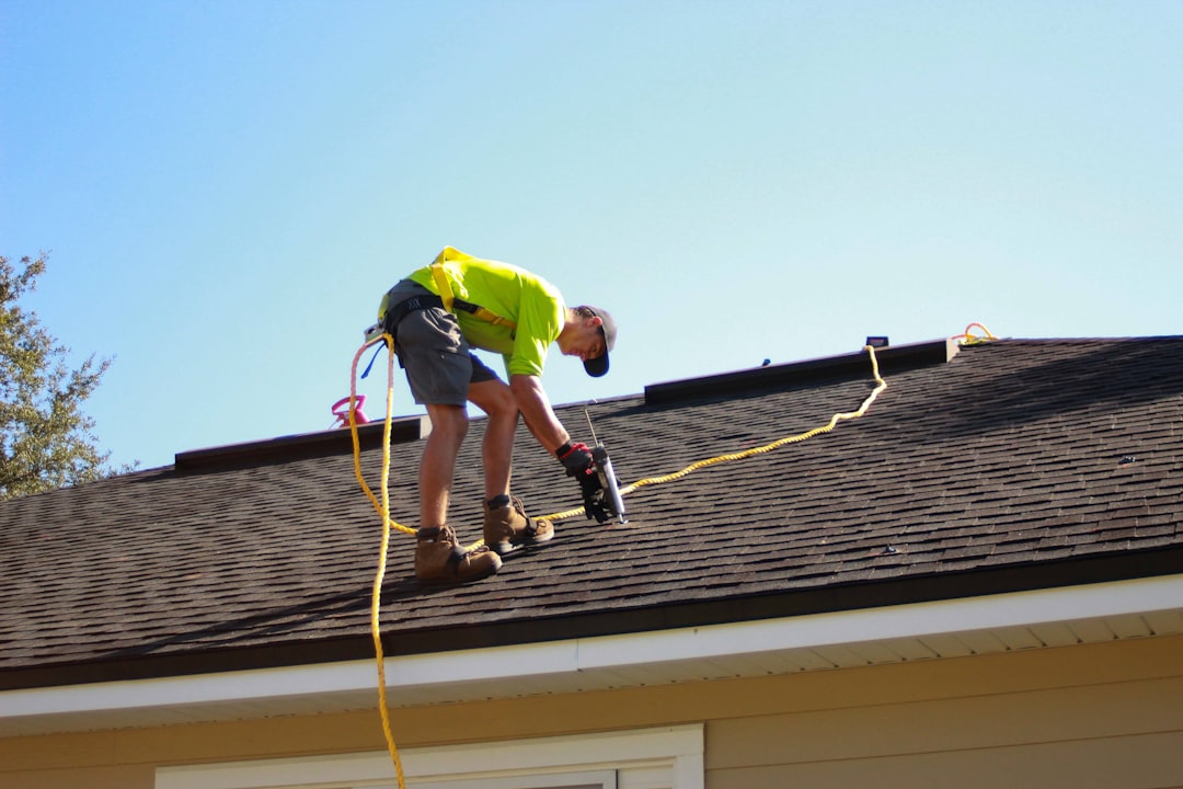 Roofer fixing battens with a power drill on a bright day