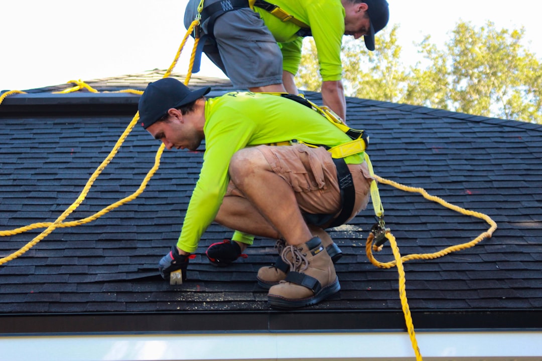 Two roofers working together on a pitched roof